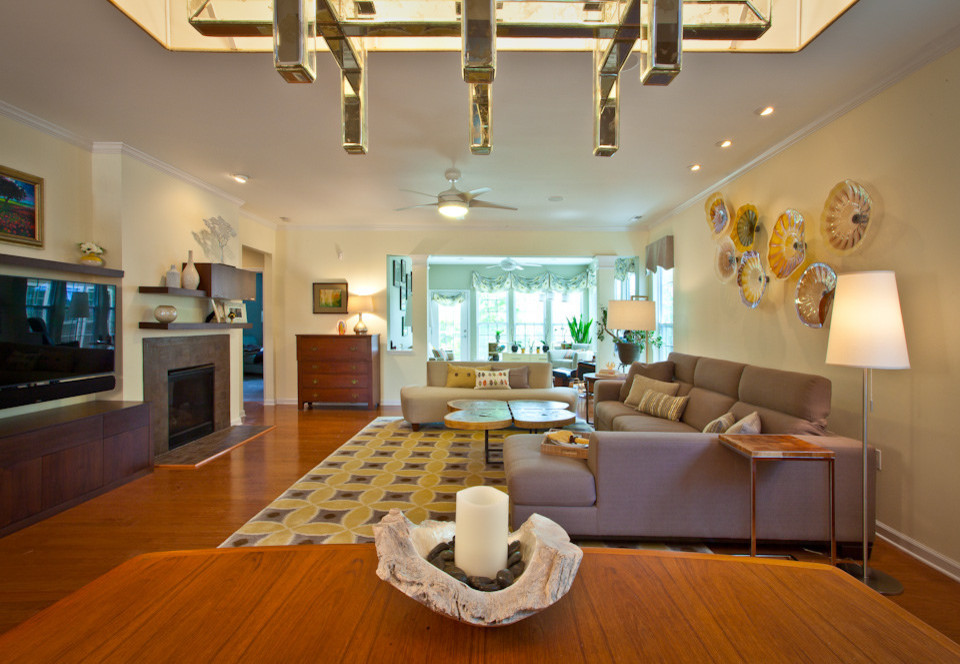 Стильный дизайн: гостиная комната в стиле фьюжн с желтыми стенами, стандартным камином, фасадом камина из плитки и телевизором на стене - последний тренд