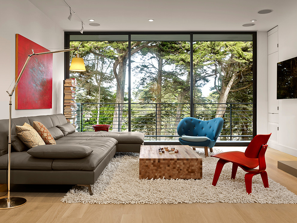 Idéer för ett modernt vardagsrum, med vita väggar, ljust trägolv och en väggmonterad TV