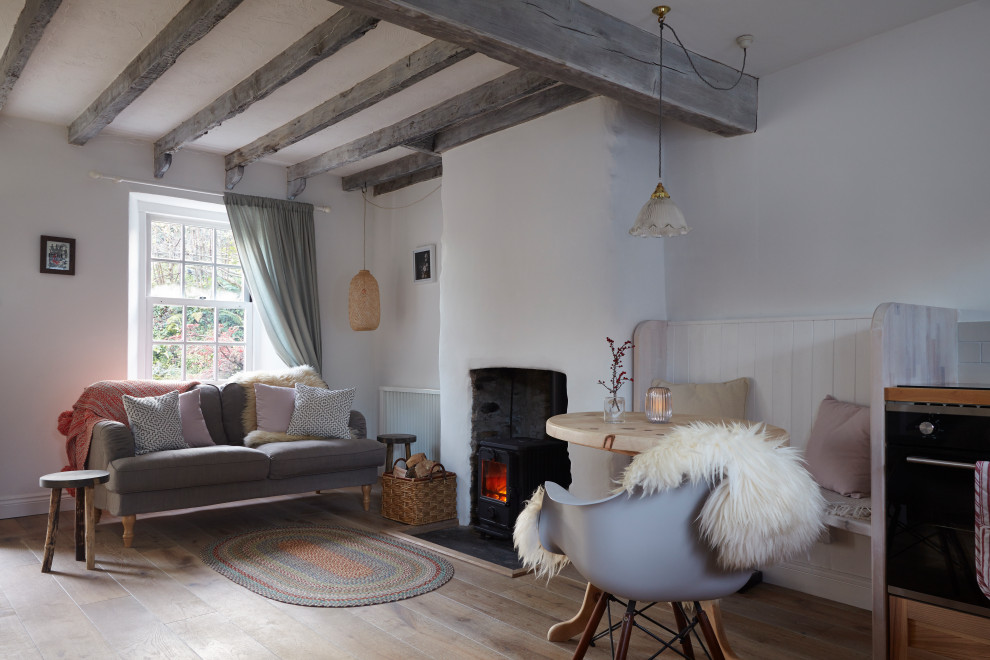 Photo of a scandi open plan living room with white walls, medium hardwood flooring, a wood burning stove, a metal fireplace surround, brown floors and exposed beams.
