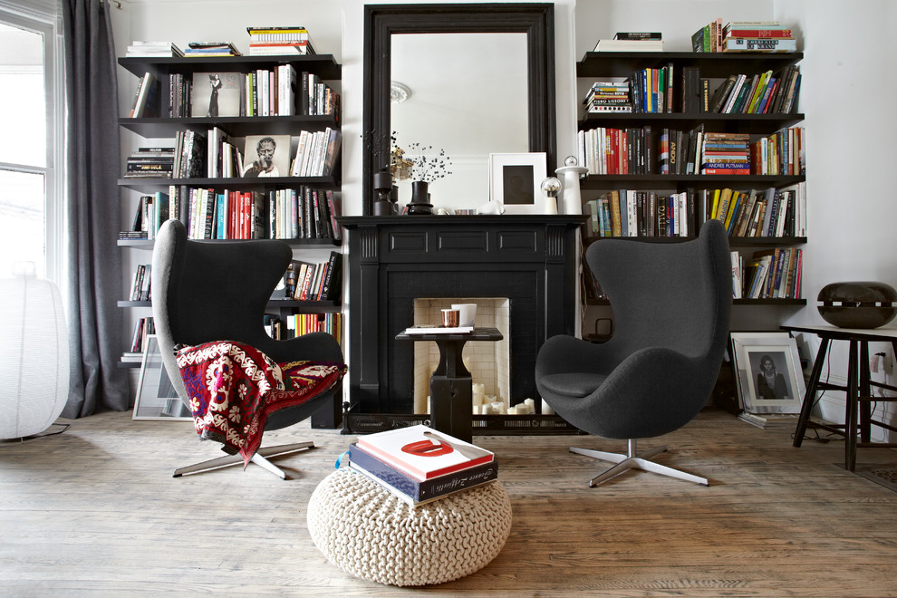 Modelo de biblioteca en casa contemporánea, sin televisor, con paredes blancas, suelo de madera en tonos medios, todas las chimeneas, marco de chimenea de madera y cortinas