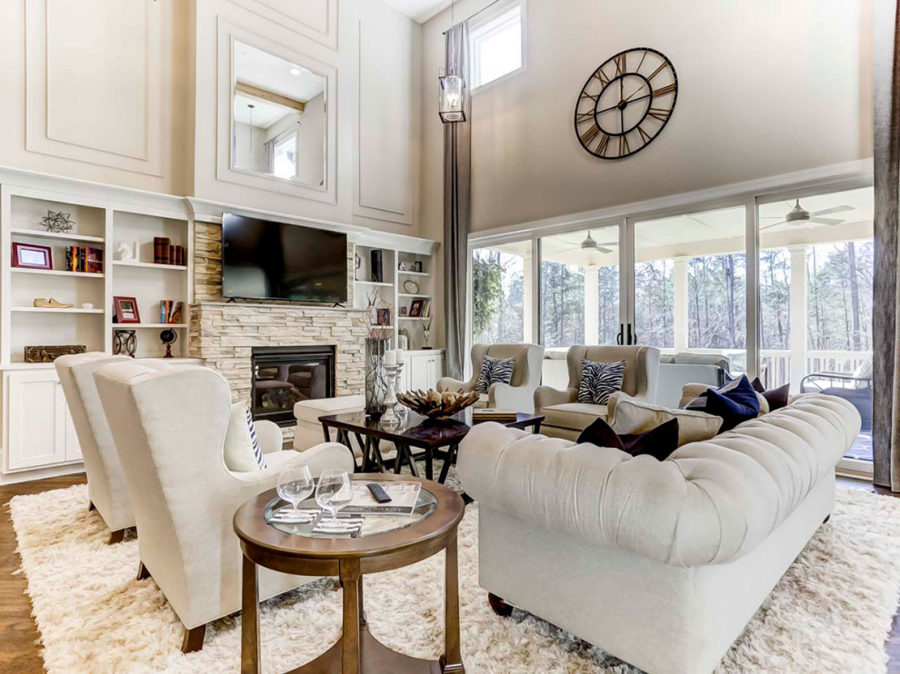 This is an example of an expansive open plan living room in Charlotte with white walls, medium hardwood flooring, a standard fireplace, a stacked stone fireplace surround, a built-in media unit, exposed beams and panelled walls.