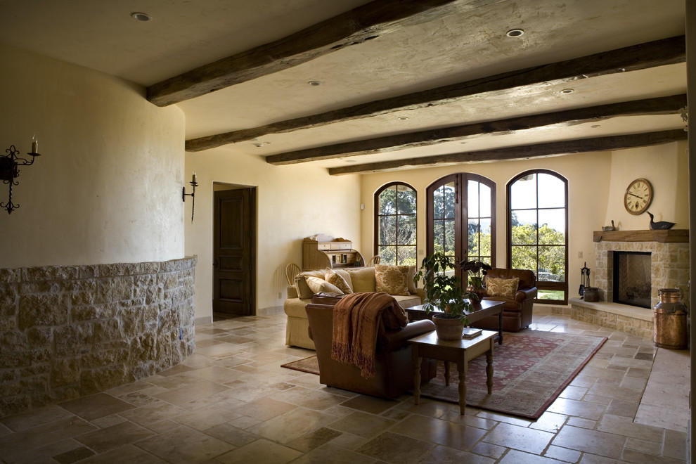 Foto de salón mediterráneo con paredes beige, chimenea de esquina, arcos y piedra