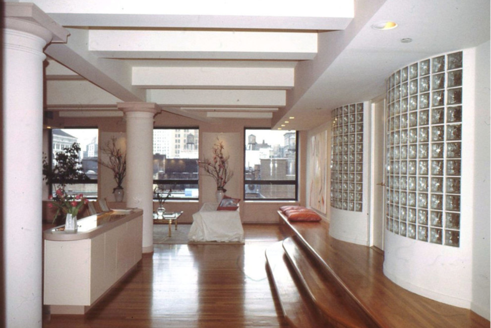 Example of a large minimalist loft-style medium tone wood floor and brown floor living room design in New York with pink walls