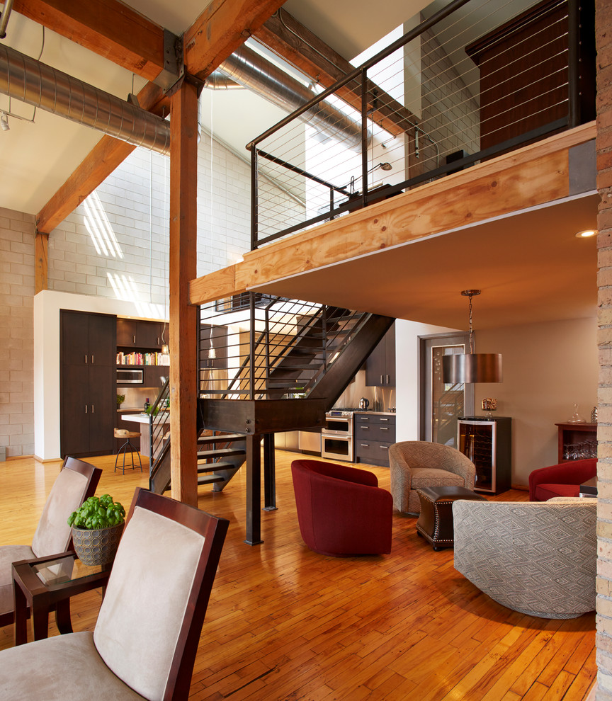 Imagen de salón abierto industrial con paredes beige y suelo de madera en tonos medios