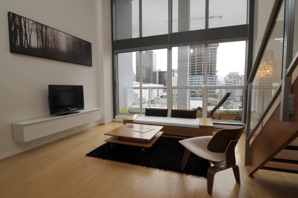 На фото: гостиная комната в современном стиле с светлым паркетным полом и отдельно стоящим телевизором с
