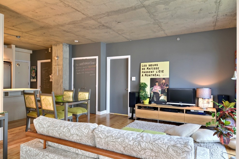 Diseño de salón abierto actual con paredes grises y suelo de madera en tonos medios