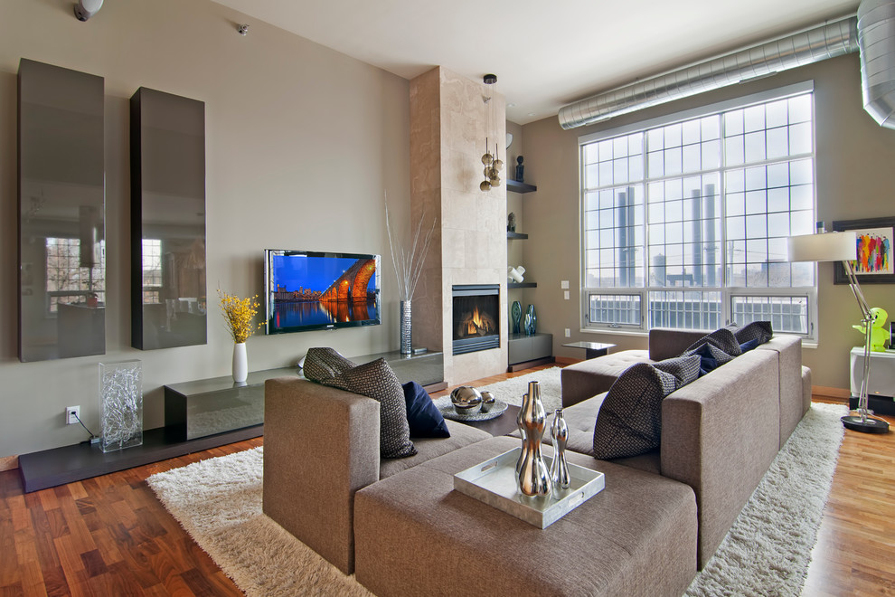 Immagine di un soggiorno minimal aperto con pareti grigie, pavimento in legno massello medio, camino classico e TV a parete