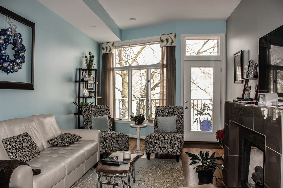 Modelo de salón abierto tradicional renovado de tamaño medio con paredes azules, suelo de madera oscura, todas las chimeneas, marco de chimenea de baldosas y/o azulejos y televisor colgado en la pared