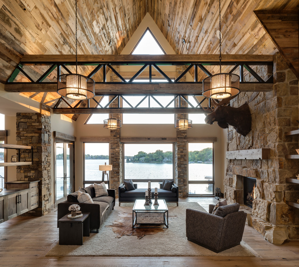 Example of a mountain style open concept medium tone wood floor and beige floor living room design in Minneapolis with beige walls, a standard fireplace and a stone fireplace
