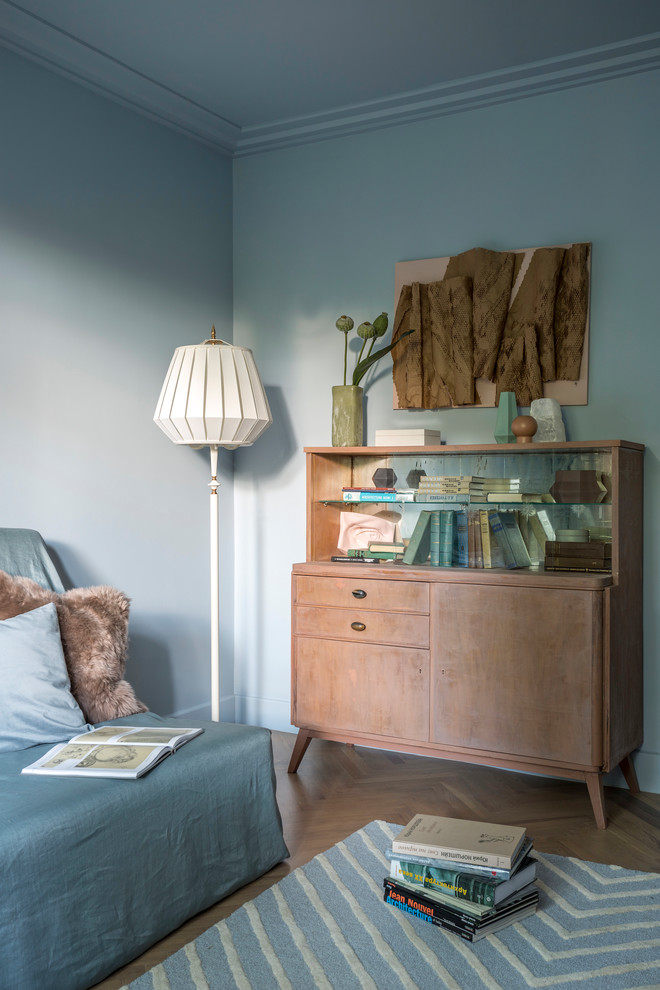 Minimalistisk inredning av ett litet separat vardagsrum, med ett finrum, blå väggar och ljust trägolv
