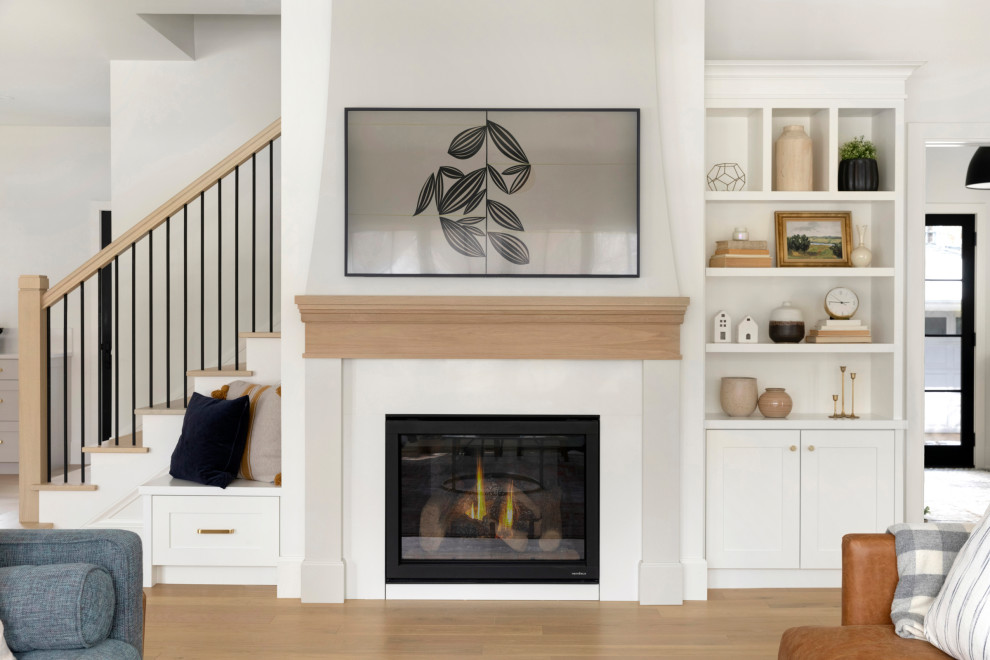 Classic open plan living room in Minneapolis with white walls, medium hardwood flooring, a standard fireplace, a wall mounted tv and brown floors.