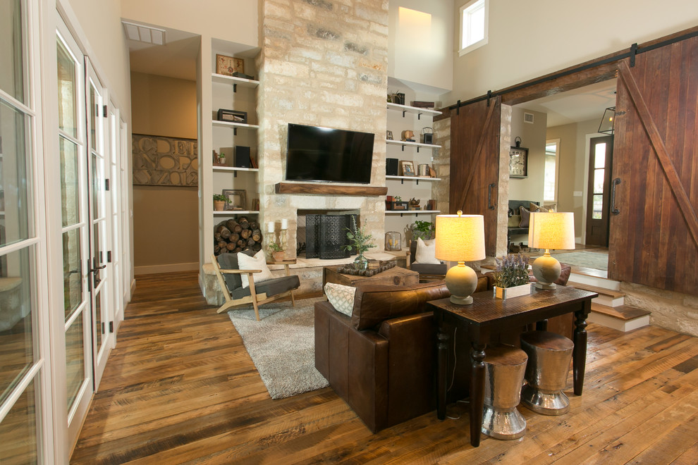 Offenes Landhausstil Wohnzimmer mit beiger Wandfarbe, braunem Holzboden, Kamin und Kaminumrandung aus Stein in Austin