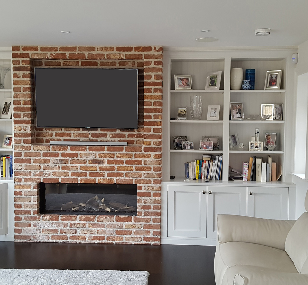Cette image montre un salon design avec un mur blanc, parquet foncé, une cheminée ribbon, un manteau de cheminée en brique et un téléviseur fixé au mur.