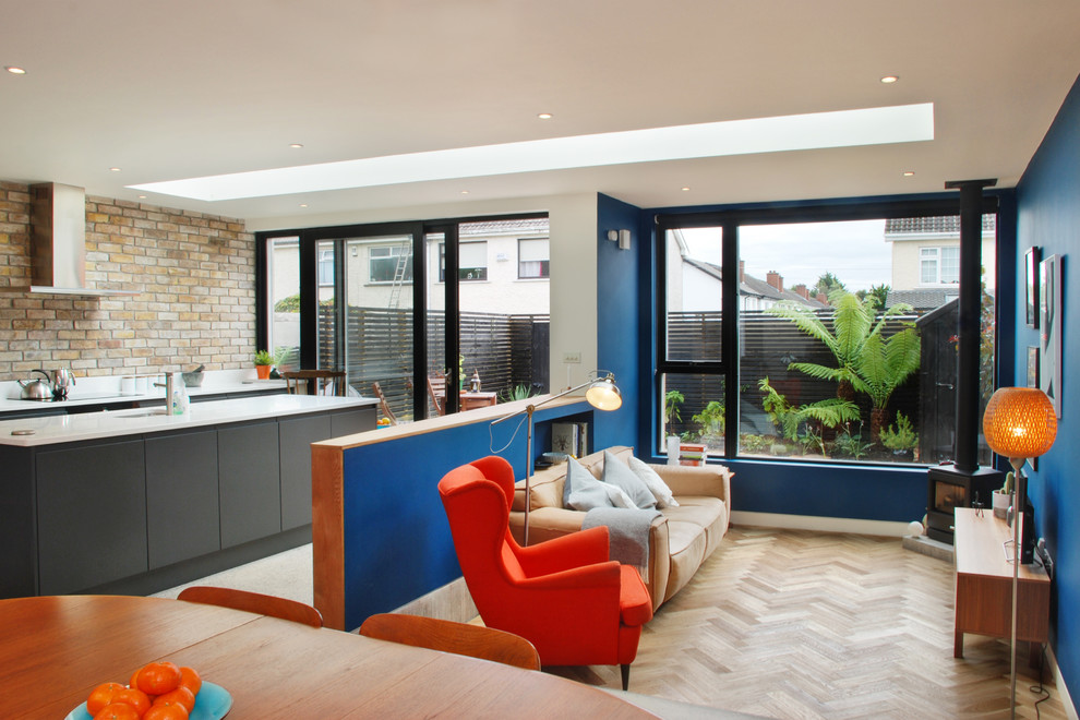 Mittelgroßes, Offenes Modernes Wohnzimmer mit blauer Wandfarbe, braunem Holzboden und Kaminofen in Dublin