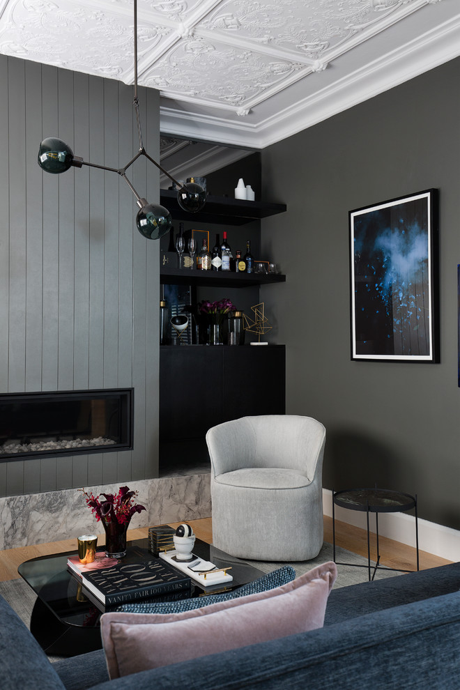 На фото: гостиная комната в современном стиле с серыми стенами, светлым паркетным полом, стандартным камином, бежевым полом и синим диваном без телевизора