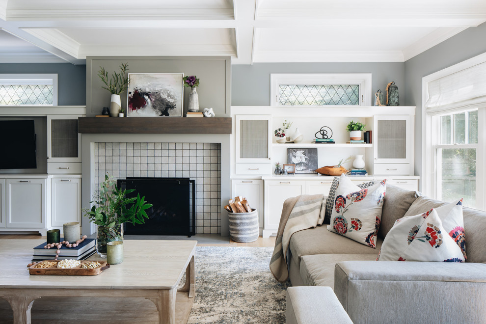 Cette image montre un grand salon traditionnel ouvert avec un mur gris, parquet clair, une cheminée standard, un manteau de cheminée en carrelage, un téléviseur encastré et un sol marron.