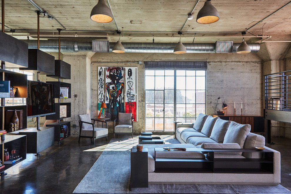 Immagine di un soggiorno industriale con pavimento in cemento, pavimento grigio, pareti grigie e TV a parete