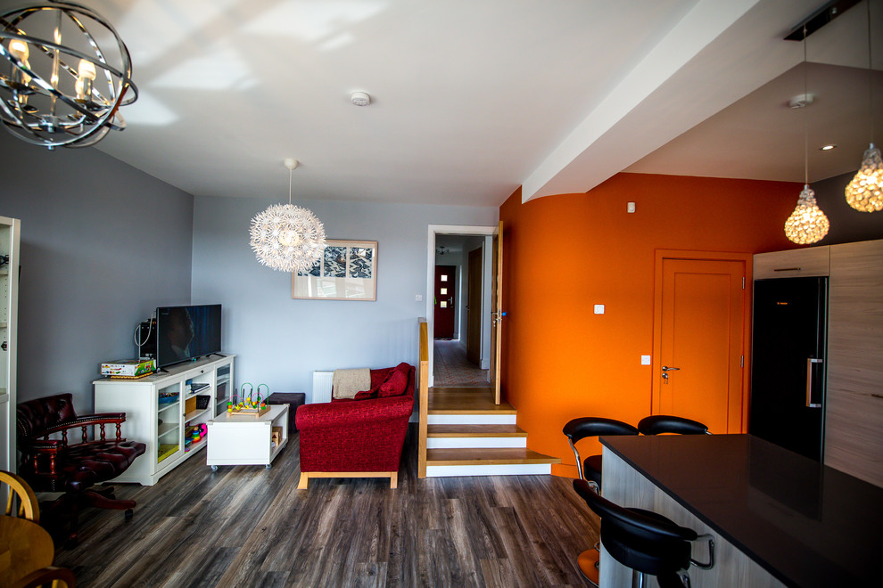 Diseño de salón contemporáneo sin chimenea con paredes multicolor, suelo de madera en tonos medios y televisor independiente