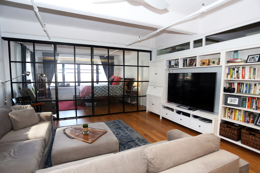 This is an example of a medium sized contemporary formal mezzanine living room in New York with white walls, medium hardwood flooring, no fireplace and a built-in media unit.