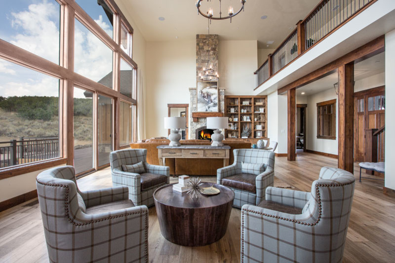 Example of a large mountain style formal and open concept light wood floor living room design in Salt Lake City with beige walls, a standard fireplace, a stone fireplace and no tv