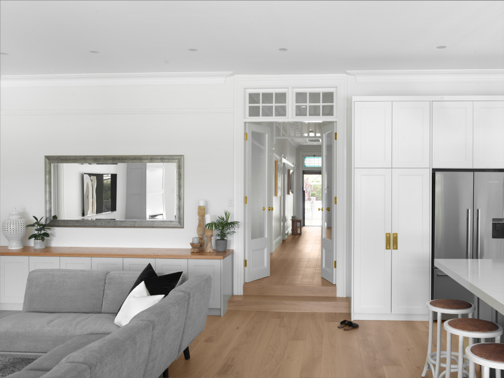 Großes, Offenes Klassisches Wohnzimmer mit gelber Wandfarbe, hellem Holzboden, Kamin, Kaminumrandung aus Holz, TV-Wand und beigem Boden in Sydney