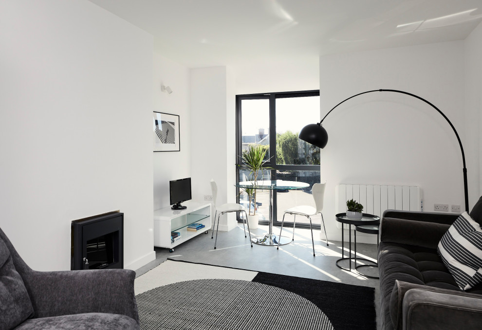 This is an example of a medium sized contemporary open plan living room in Dublin with vinyl flooring, a standard fireplace, a plastered fireplace surround, a freestanding tv and grey floors.