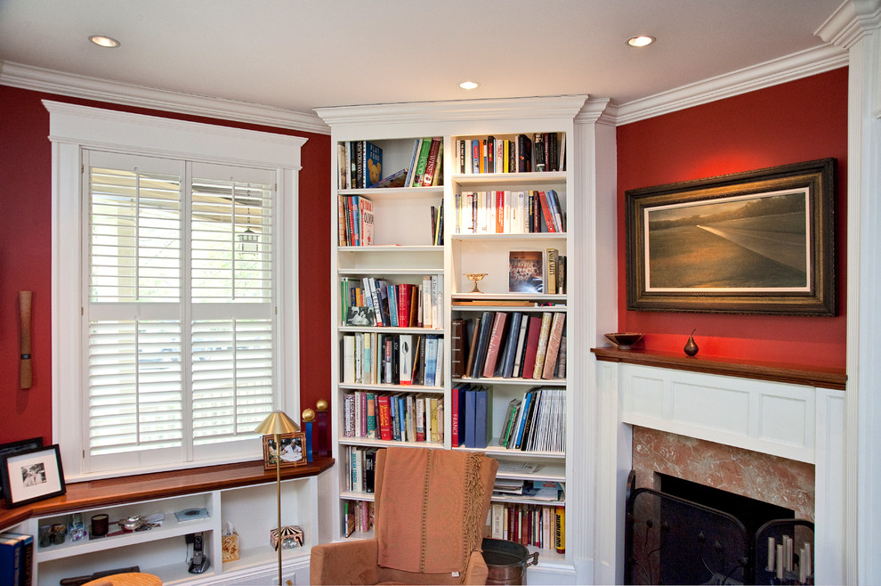 Immagine di un soggiorno chic di medie dimensioni con libreria, pareti rosse, camino ad angolo e cornice del camino in pietra