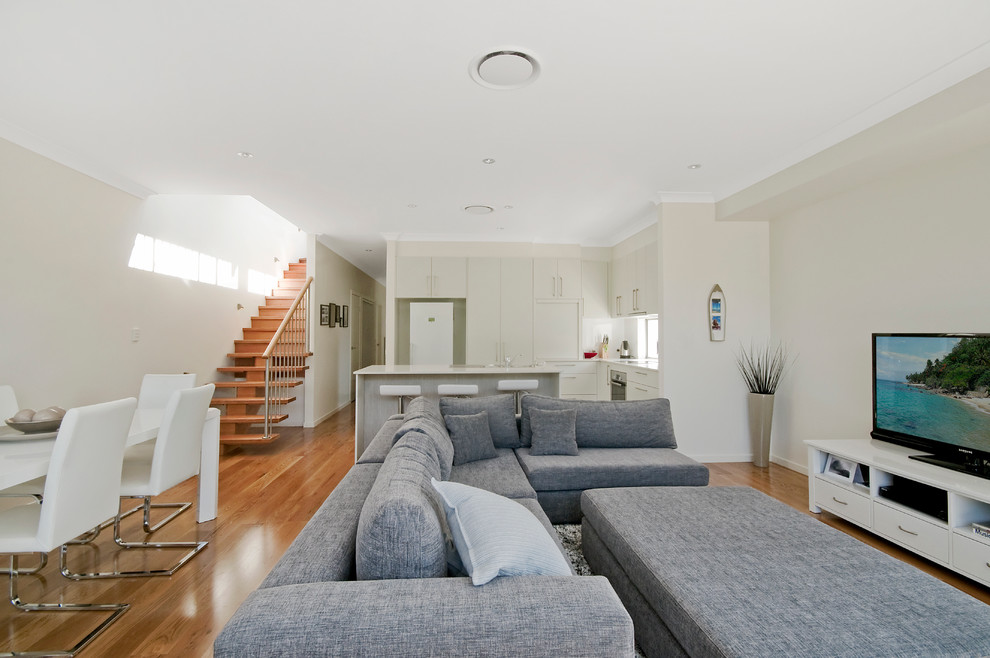 Offenes Modernes Wohnzimmer mit beiger Wandfarbe, braunem Holzboden und freistehendem TV in Gold Coast - Tweed