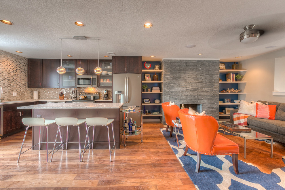 Mittelgroßes, Offenes Modernes Wohnzimmer mit bunten Wänden, braunem Holzboden, Kamin und Kaminumrandung aus Stein in Kansas City