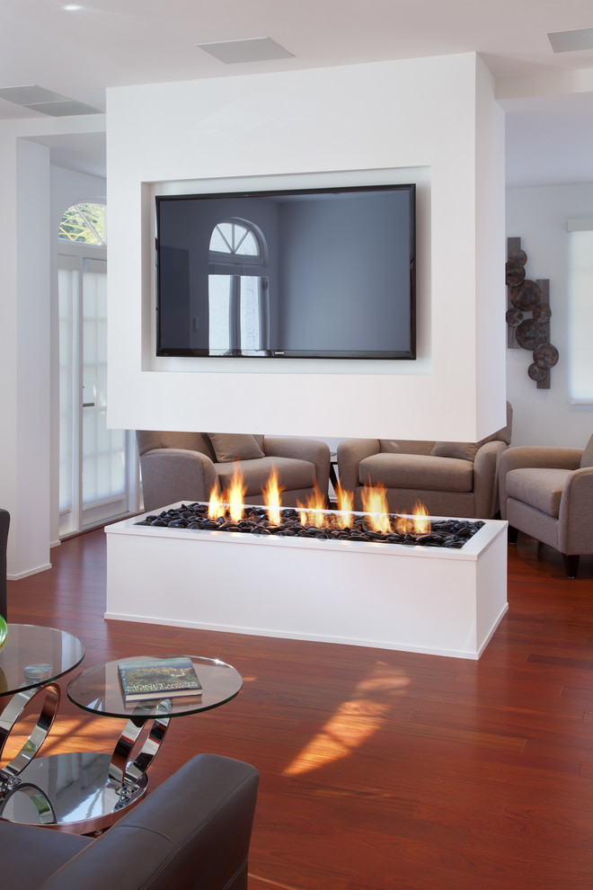 Imagen de salón abierto contemporáneo con suelo de madera en tonos medios, chimenea lineal y televisor colgado en la pared