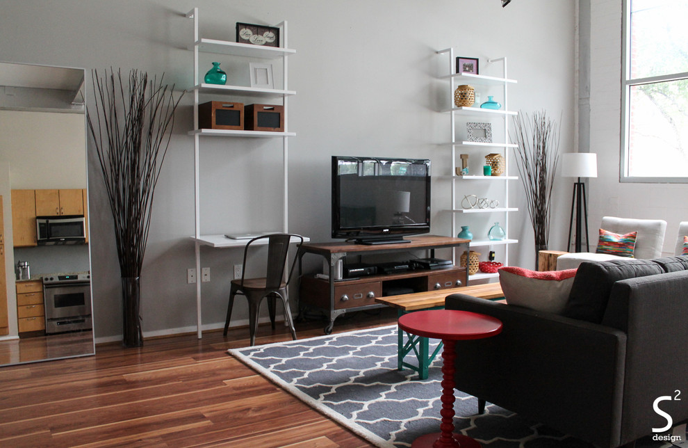 Ejemplo de salón tipo loft urbano con paredes grises, suelo de madera en tonos medios y televisor independiente