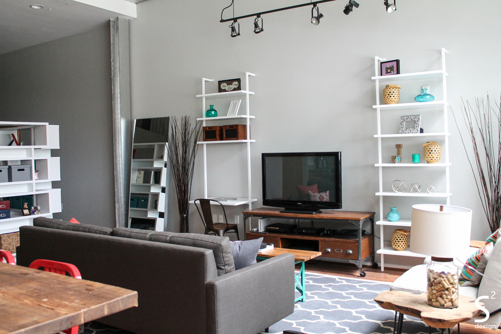 Свежая идея для дизайна: двухуровневая гостиная комната в стиле лофт с серыми стенами, паркетным полом среднего тона и отдельно стоящим телевизором - отличное фото интерьера