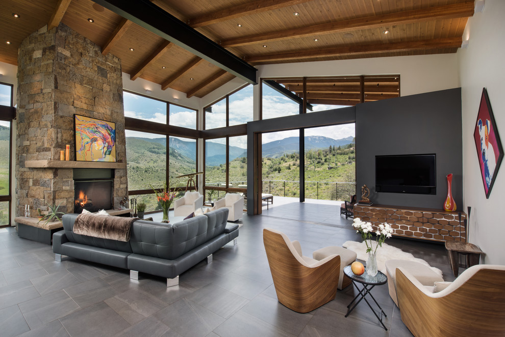 Design ideas for an expansive contemporary open plan living room in Denver with white walls, porcelain flooring, a standard fireplace, a stone fireplace surround, a wall mounted tv and grey floors.
