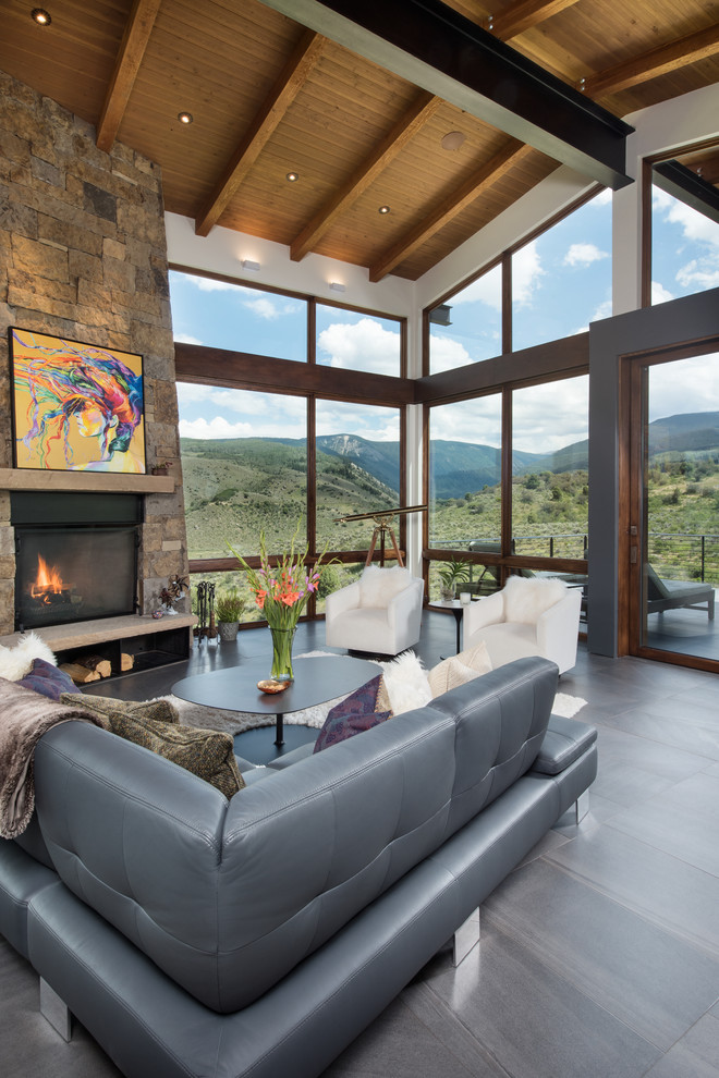 Inspiration for an expansive contemporary open plan living room in Denver with white walls, porcelain flooring, a standard fireplace, a stone fireplace surround, a wall mounted tv and grey floors.