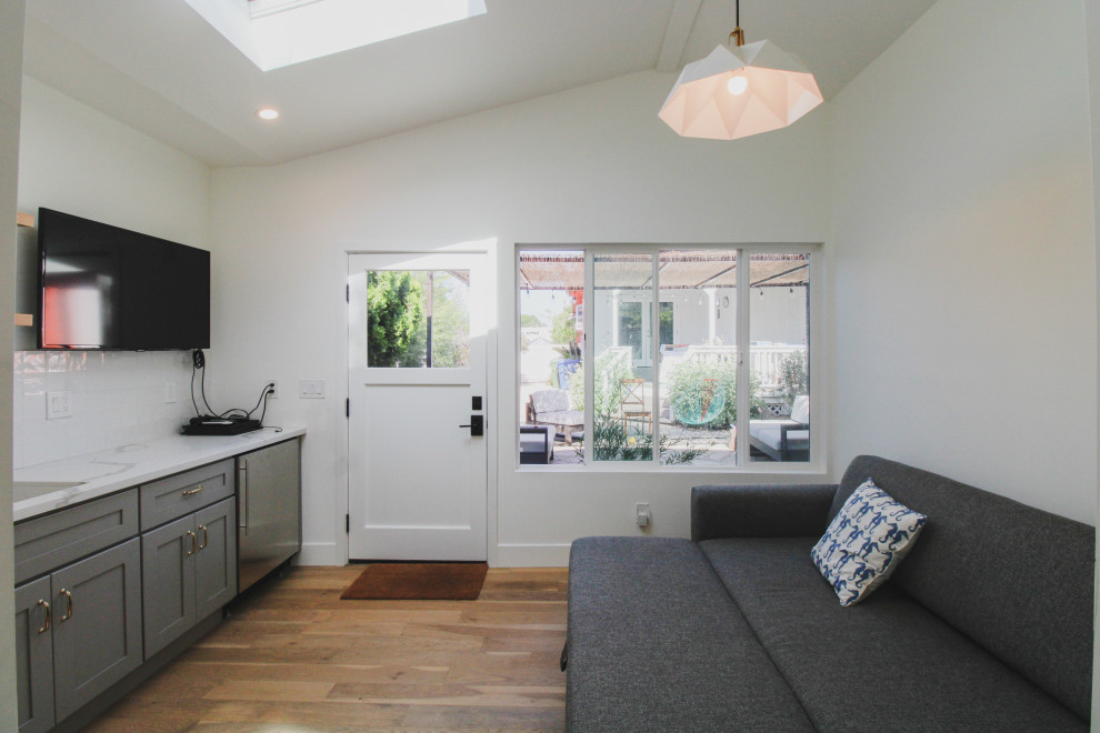 Inspiration för små klassiska separata vardagsrum, med vita väggar, laminatgolv, en väggmonterad TV och brunt golv