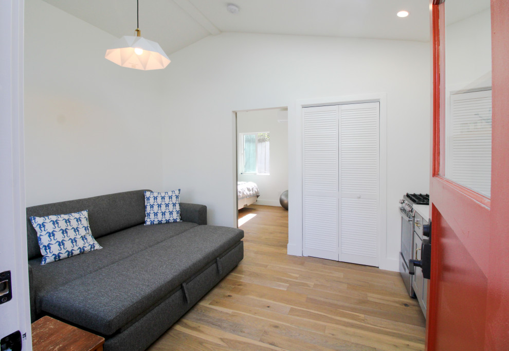 Inspiration för ett litet vintage loftrum, med vita väggar, laminatgolv, en väggmonterad TV och brunt golv