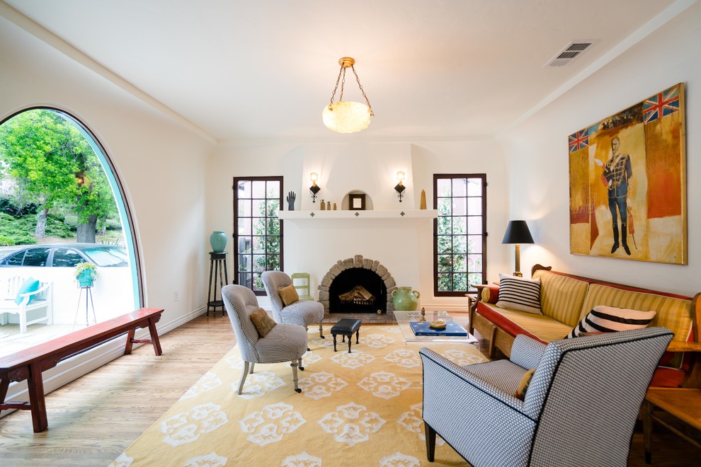 Repräsentatives, Fernseherloses Klassisches Wohnzimmer mit weißer Wandfarbe, Kamin, braunem Holzboden und Kaminumrandung aus Stein in Los Angeles