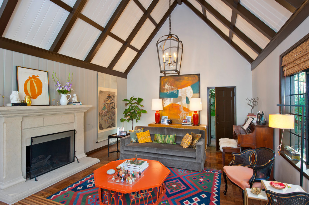Stilmix Wohnzimmer mit weißer Wandfarbe, braunem Holzboden, Kamin, braunem Boden, freigelegten Dachbalken, gewölbter Decke und Holzdielenwänden in Los Angeles