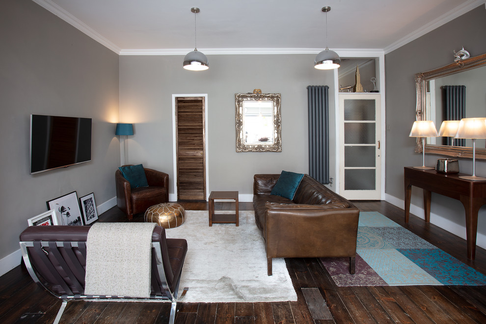 На фото: изолированная гостиная комната среднего размера в современном стиле с серыми стенами, темным паркетным полом, телевизором на стене и коричневым полом с