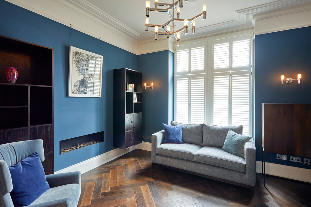 Modern inredning av ett mellanstort separat vardagsrum, med ett finrum, blå väggar, mörkt trägolv, en bred öppen spis, en spiselkrans i gips och brunt golv