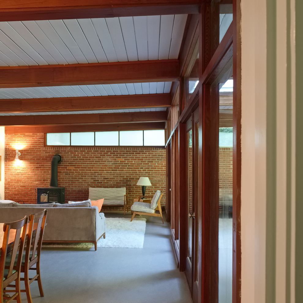 Источник вдохновения для домашнего уюта: открытая гостиная комната среднего размера в стиле ретро с белыми стенами, печью-буржуйкой, полом из линолеума и фасадом камина из кирпича