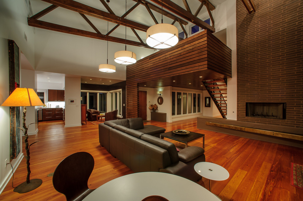 Idées déco pour un grand salon contemporain ouvert avec une salle de réception, un sol en bois brun, un mur blanc, une cheminée standard, un manteau de cheminée en brique et un sol marron.