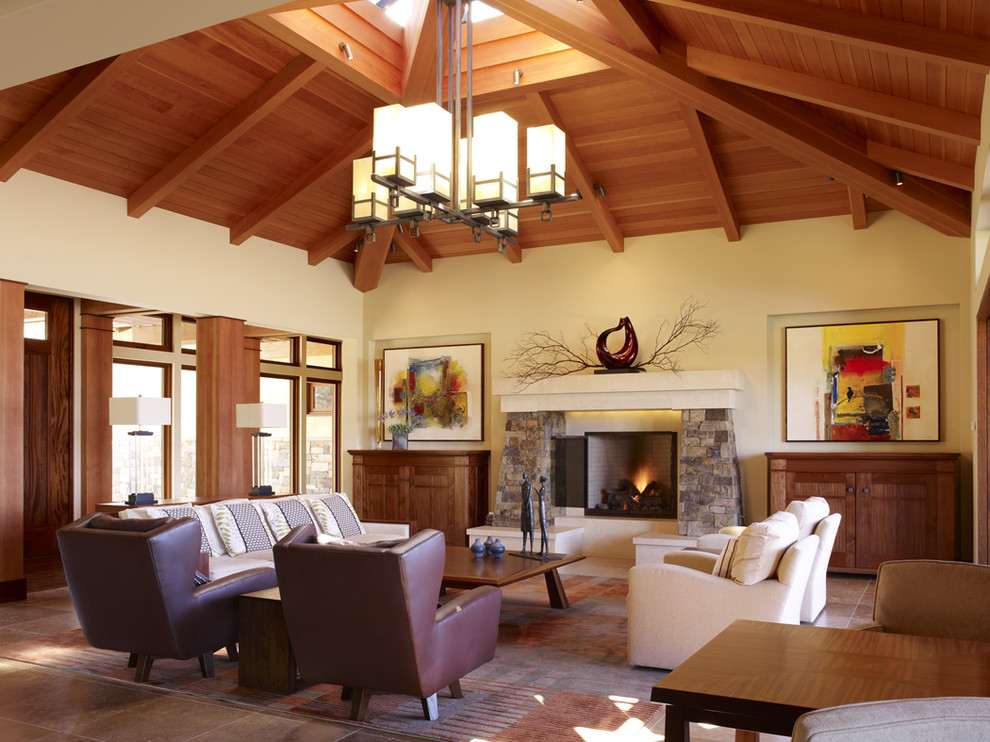 Exemple d'un très grand salon tendance ouvert avec un mur beige, un sol en bois brun, une cheminée standard, un manteau de cheminée en pierre et un sol marron.