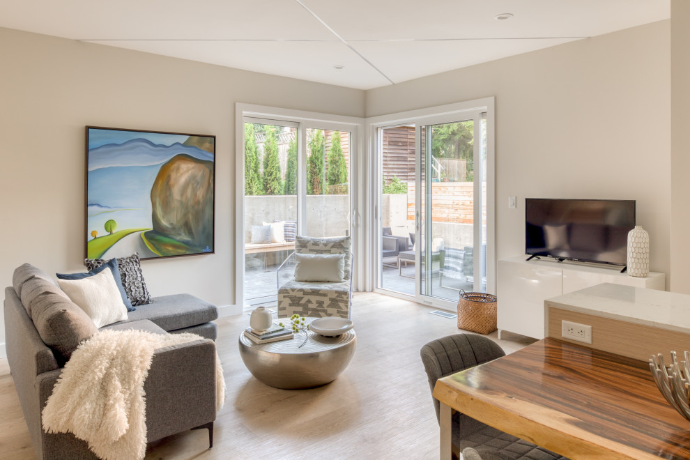 This is an example of a medium sized modern open plan living room in Vancouver with grey walls, light hardwood flooring, no fireplace, a freestanding tv and beige floors.