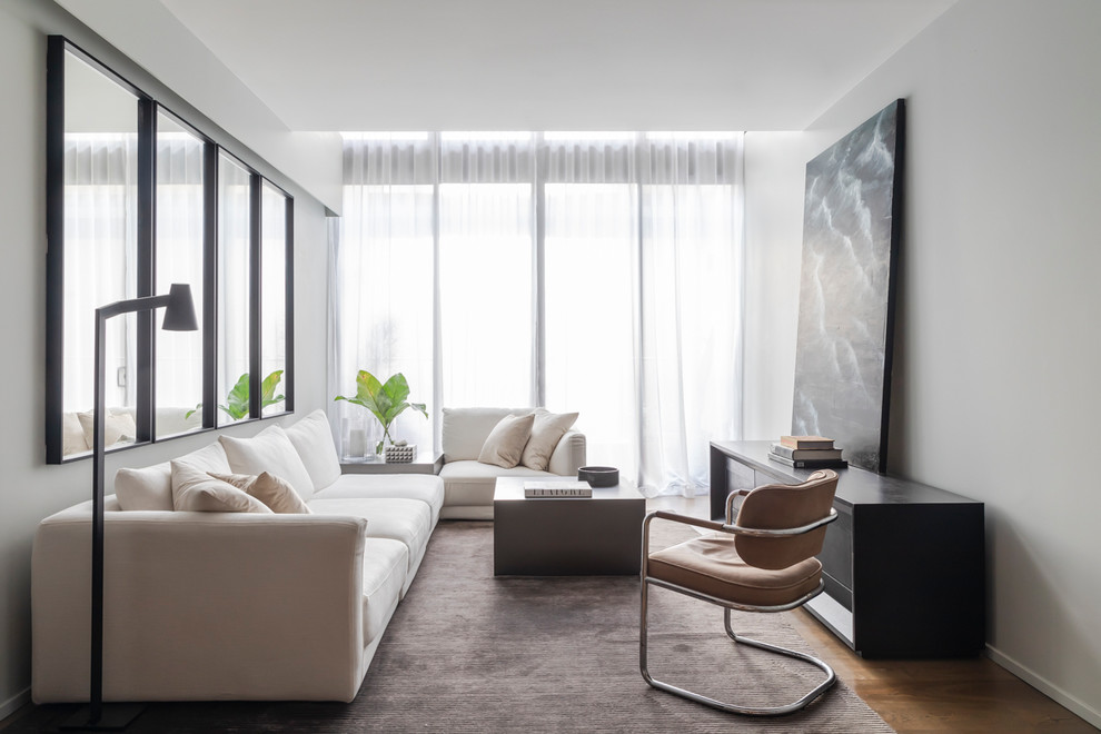 Cette image montre un petit salon design ouvert avec un mur gris, un sol en bois brun, un sol marron et éclairage.
