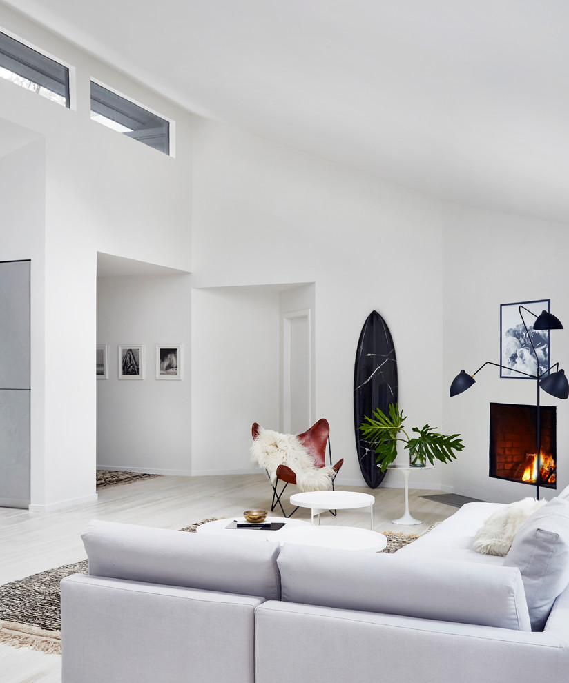 Пример оригинального дизайна: парадная, открытая гостиная комната среднего размера в скандинавском стиле с белыми стенами, светлым паркетным полом, стандартным камином, фасадом камина из штукатурки и бежевым полом без телевизора