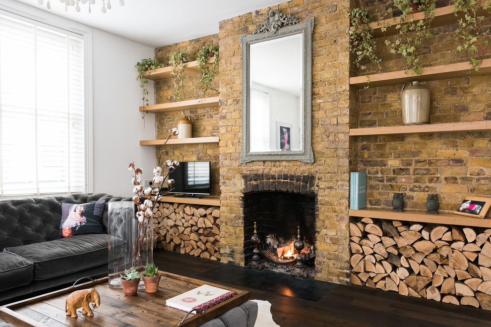 ロンドンにある広い地中海スタイルのおしゃれなLDK (濃色無垢フローリング、白い壁、標準型暖炉、レンガの暖炉まわり、据え置き型テレビ、茶色い床) の写真