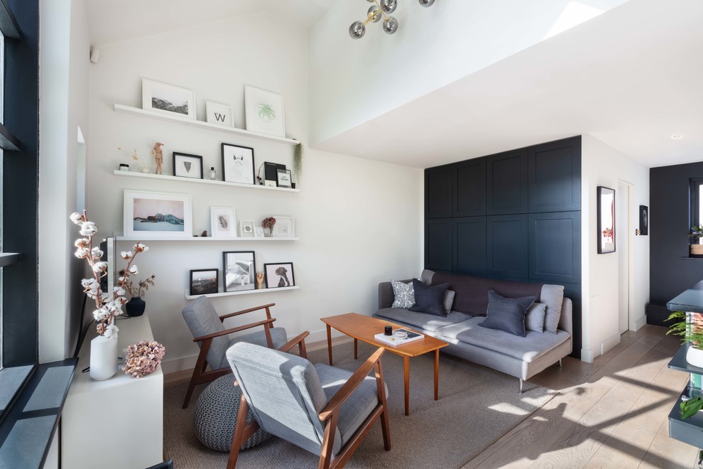 Exemple d'un salon tendance de taille moyenne et ouvert avec un mur blanc, parquet clair, un téléviseur indépendant et un sol beige.