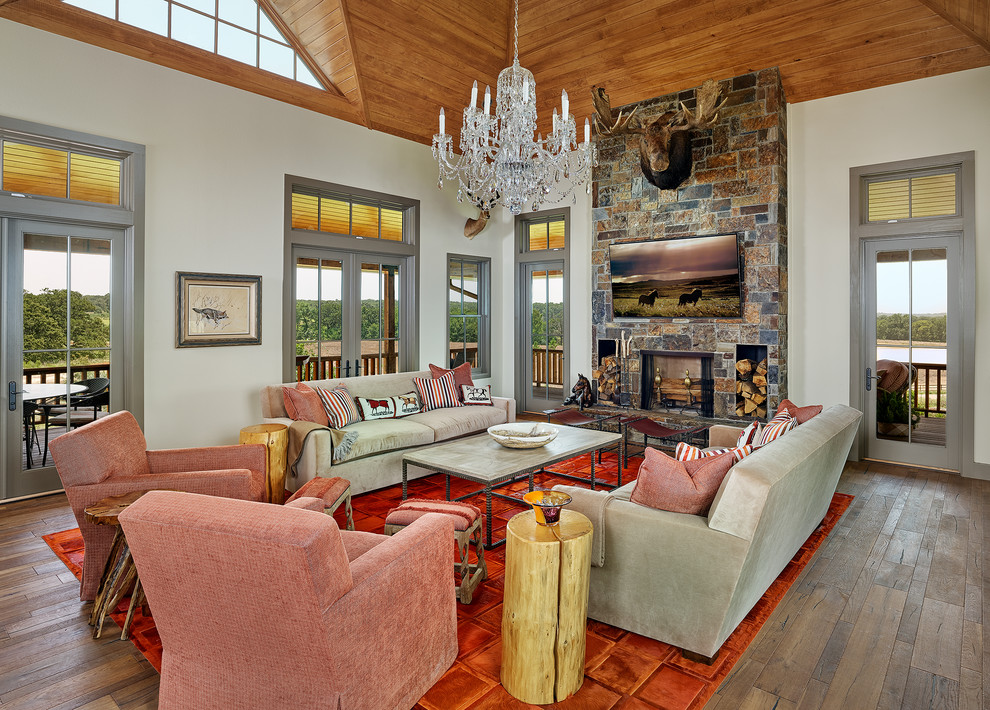 Mid-sized southwest open concept medium tone wood floor and brown floor living room photo in Dallas with beige walls, a standard fireplace, a stone fireplace and a wall-mounted tv