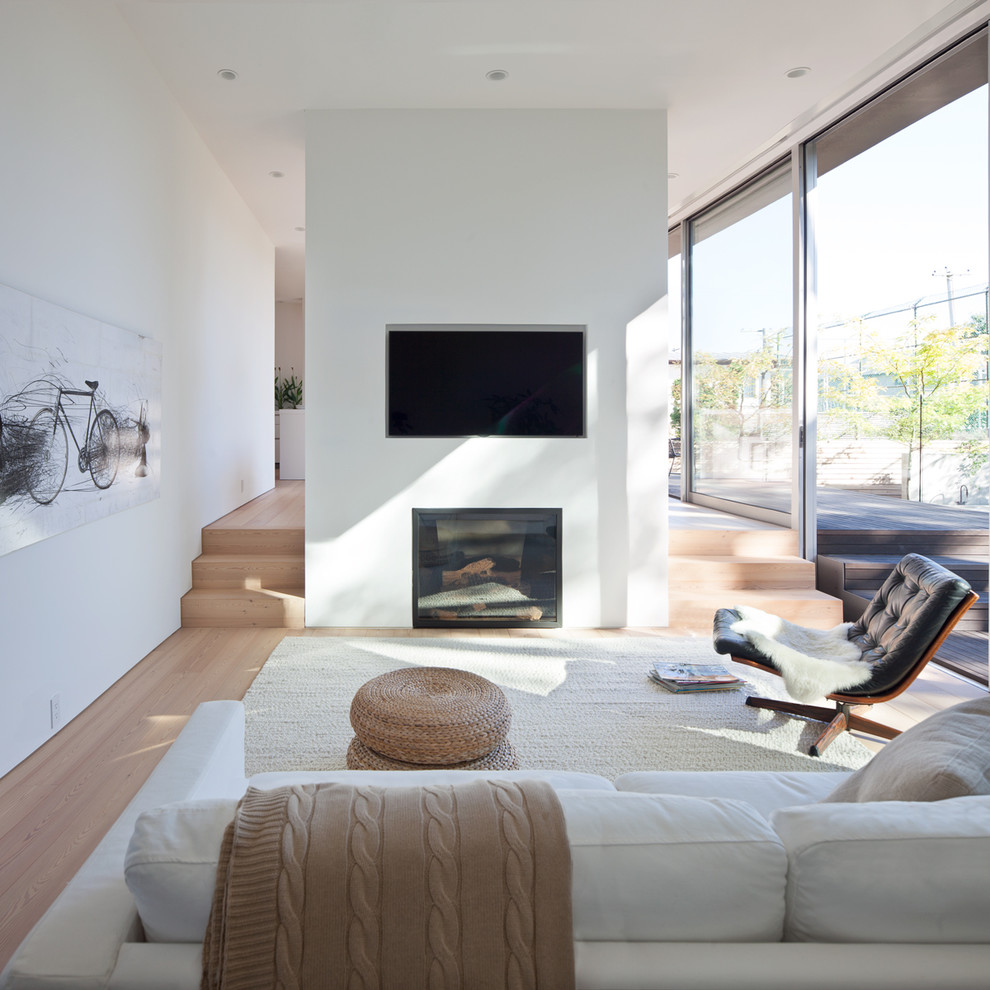 Inspiration for a mid-sized modern open concept medium tone wood floor living room remodel in Vancouver with white walls, a standard fireplace, a plaster fireplace and a media wall